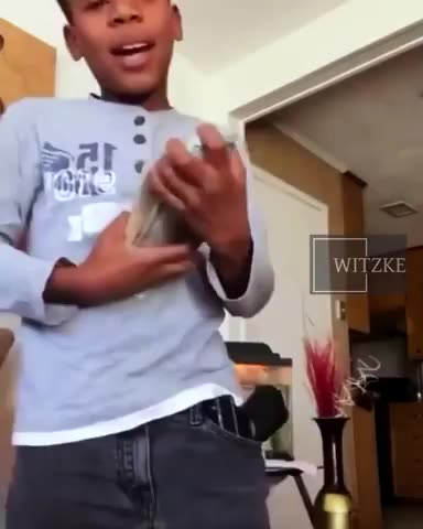 7 year old nigglet pointing a hand gun at camera while flashing cash
