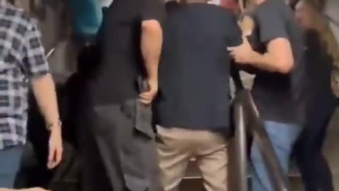 In UK, a black man hits a white man who's holding a baby, who falls to ground.