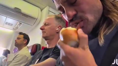 MAN BITES INTO A RAW ONION ON A PACKED FLIGHT