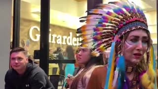 A man dressed as a woman scolds a woman dressed as an Indian for Halloween.