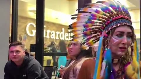 A man dressed as a woman scolds a woman dressed as an Indian for Halloween.