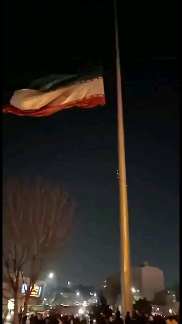 The protesters are taking down and tearing apart a huge Iranian flag in the city of Mashhad