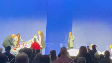 CodePink protesters rush stage with banner as Secretary of the Navy and Palantir's