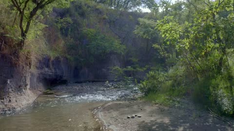 Flying over a relaxing creek full of rock on the countryside