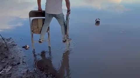 Man Uses Folding Chairs To Cross Water