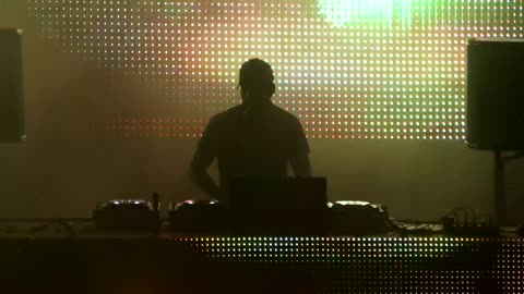 The silhouette of a DJ playing with a modern.