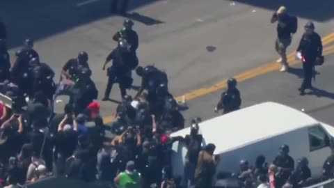 LA riots. Anti ICE guy on stilts gets pushed down.