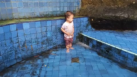 "Having Fun with Water! This Kid Enjoys the Fountain in the Swimming Pool"