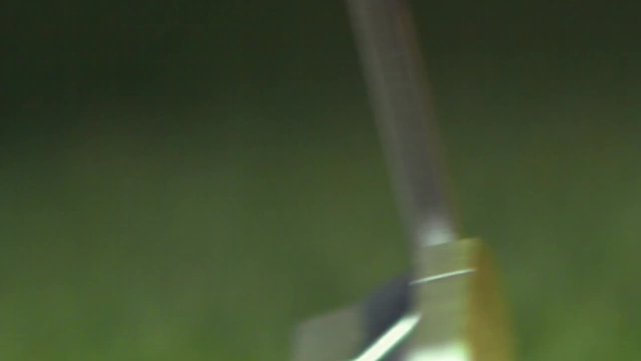 An extreme close-up of a golf putter in motion.