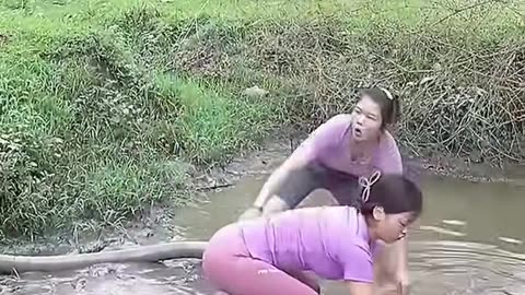 Two beautiful village girl working for catching fish from pool.