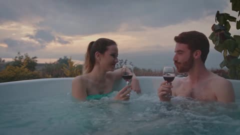 Couple drinking wine and blowing kisses in a hot tub