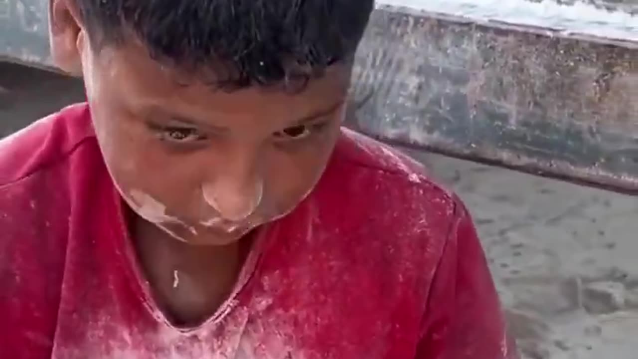 মরিয়া হয়ে মাটি থেকে ছড়িয়ে ছিটিয়ে থাকা আটা সংগ্রহ করছে এক ফিলিস্তিনি শিশু