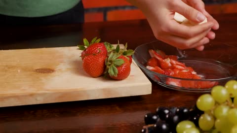 Person cutting banana on top of a wooden board.