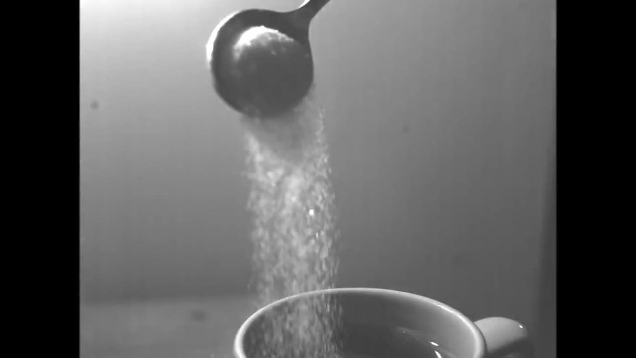 Sugar being poured into coffee cup