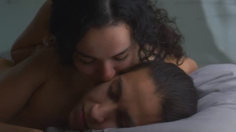 A girlfriend in love wakes up with affectionate kisses to her boyfriend.