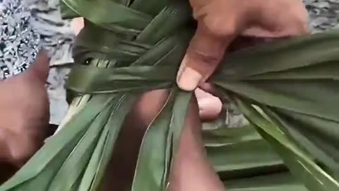 A woman from Amazon forest weaving a shoe using palm tree leaves