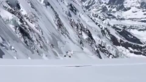 A pilot takes off just above the climbers in the mountains