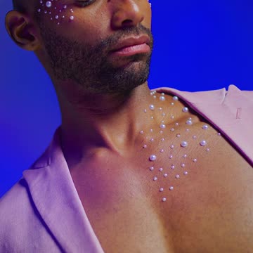 Man in stylish lighting with decorative gems on chest