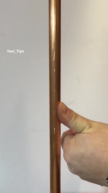 Hand Holding a Copper Pipe for Plumbing DIY