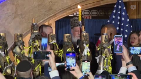 New York City mayor Eric Adams lights a giant menorah with a Rabbi while wearing a kippah.