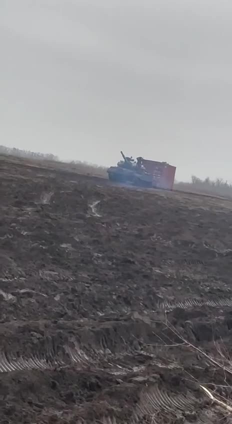Russian tank is pulling a sea container across a field, probably to build an underground shelter.