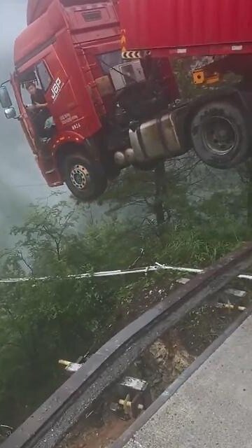 truck, with the driver inside, hangs over a collapsed bridge after a landslide in China