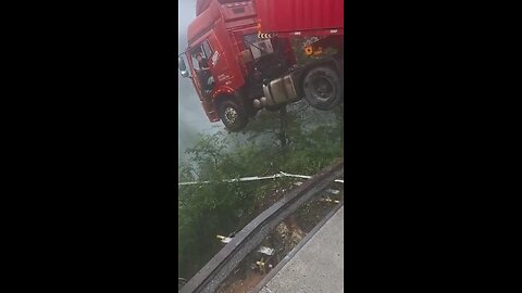 truck, with the driver inside, hangs over a collapsed bridge after a landslide in China