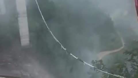 truck, with the driver inside, hangs over a collapsed bridge after a landslide in China