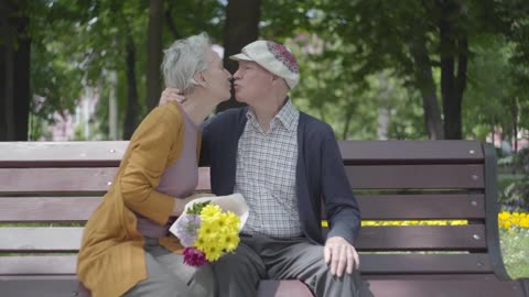 Old couple sitting on a bench in a park, Love until the end