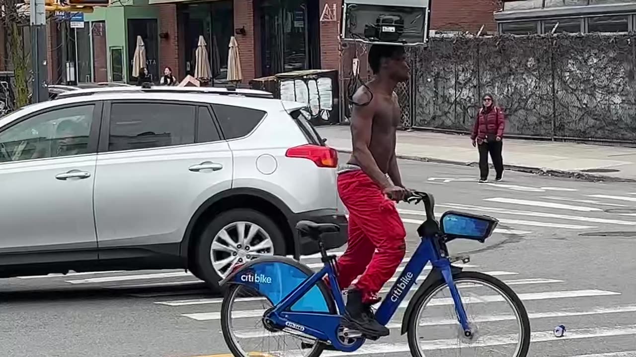 Man Rides Bike While Balancing a Fridge on His Head
