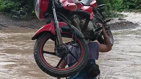 Man Carries His Motorcycle Across River