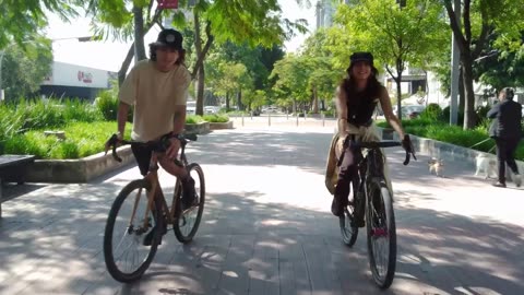 Bike ride of a young couple through a sunny city park.