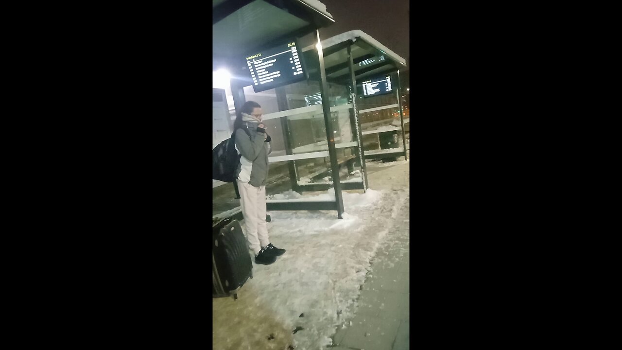 Beautiful girl in a light jacket and light pants freezes while waiting for the bus.