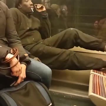 🇫🇷 On a Paris train, a migrant smokes a cigarette and sets his bare feet on an opposite seat.