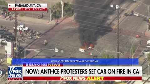 Man with a Mexican flag circles a burning car during anti-ICE unrest in Los Angeles