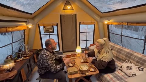 A Couple spending Time in Snow woods while setting their camp and became relax