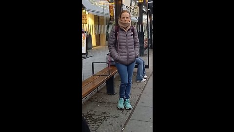 Beautiful young woman in a light autumn jacket freezing while waiting for the bus.