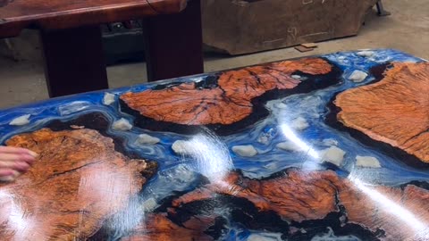 Ryan from Lumberlust Designs waxing a resin table to beautiful