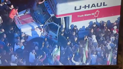 Aerial video of a U Haul entering in the crowd of a pro Iranian Shah protest