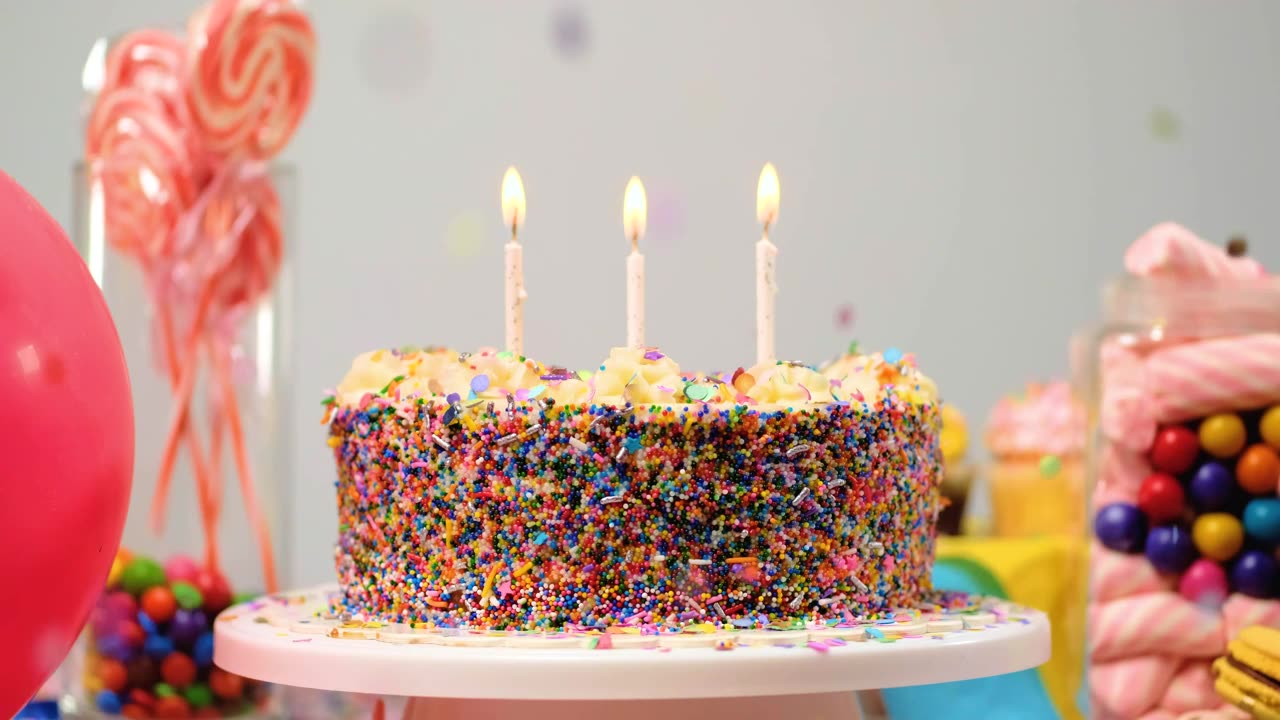 Colorful cake with burning candles on a table.