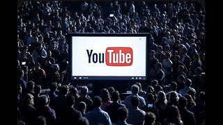 A vast crowd watches a large screen displaying a YouTube video interface in a dimly lit setting.
