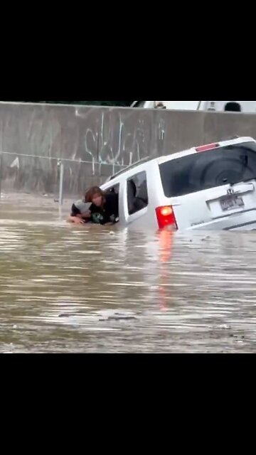 Man swims into flooded water to pull sinking woman out of trapped car
