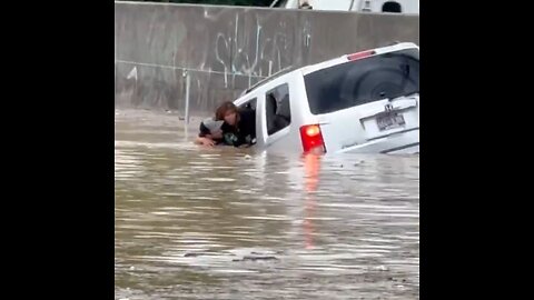 Man swims into flooded water to pull sinking woman out of trapped car