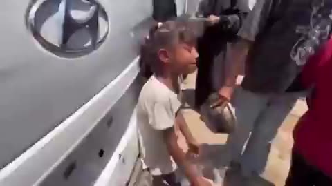 A Palestinian girl in Gaza is crying as she asks for food at an aid distribution point