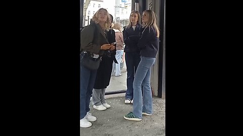 Four young beautiful girls hide the strong north wind and real feel -7°C in bus stop.