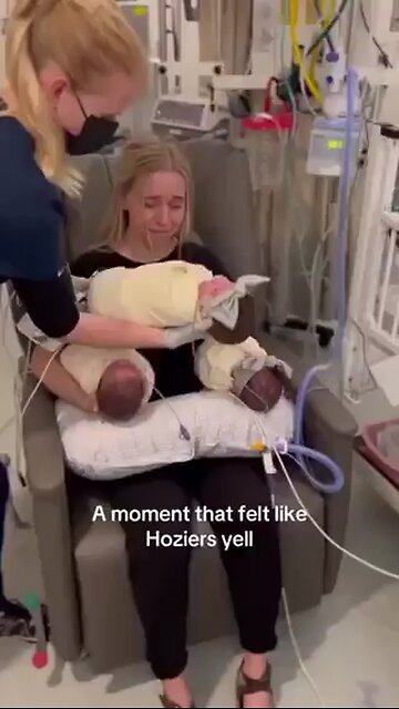 mother cries as she holds her newborn triplets for the first time