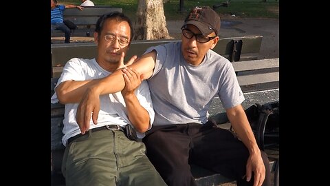 Luodong Massages Hispanic Man's Elbow On The Park Bench