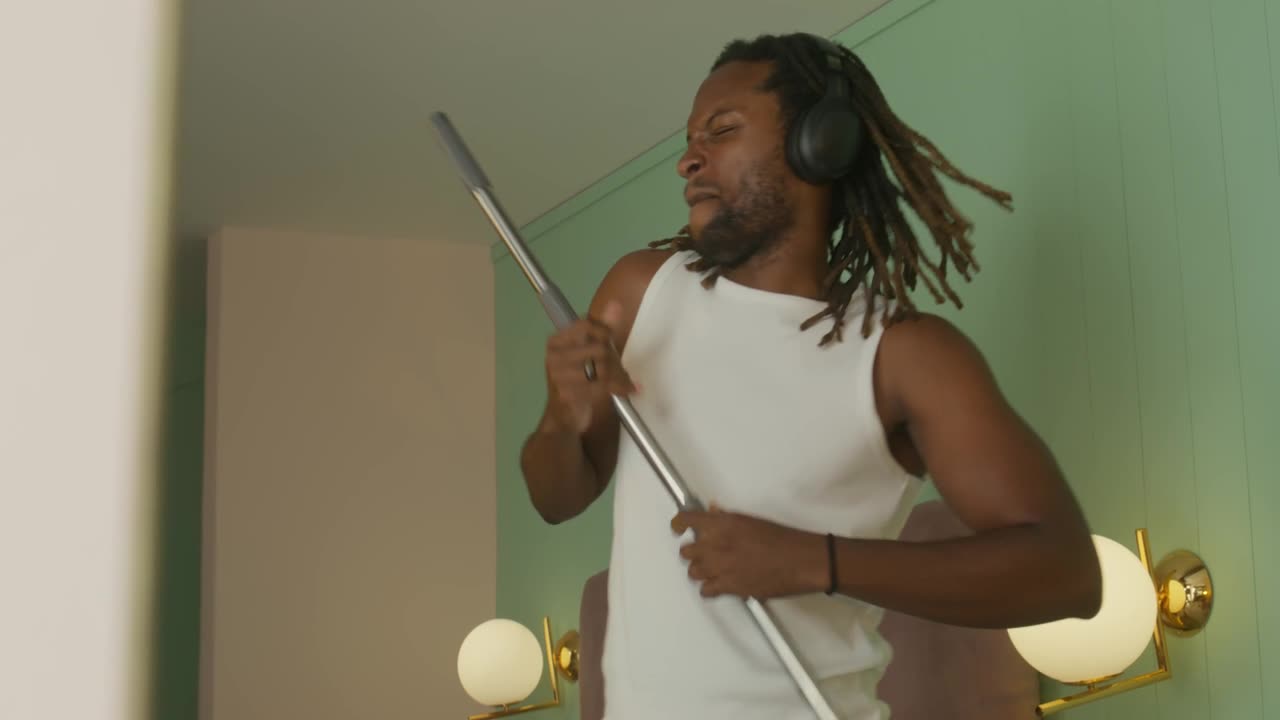 A Black man dances and sings while doing house chores, bringing pure joy to the everyday grind.
