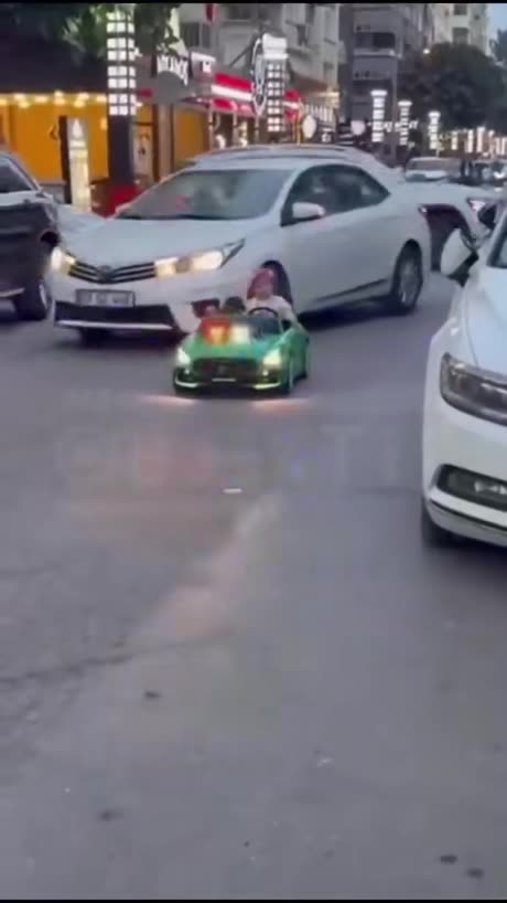 Adults responsible for this little kid let her drive a mini car in the middle of the street