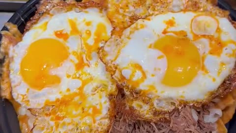 Doritos with beef and fried eggs topping with cheese and guacamole sauce
